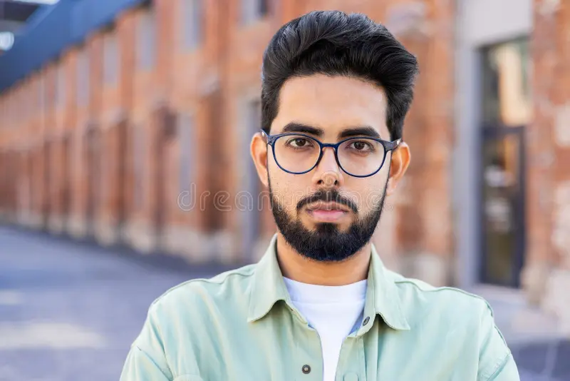 close-up-portrait-young-indian-man-standing-outside-his-forehead-looking-seriously-camera-301326364